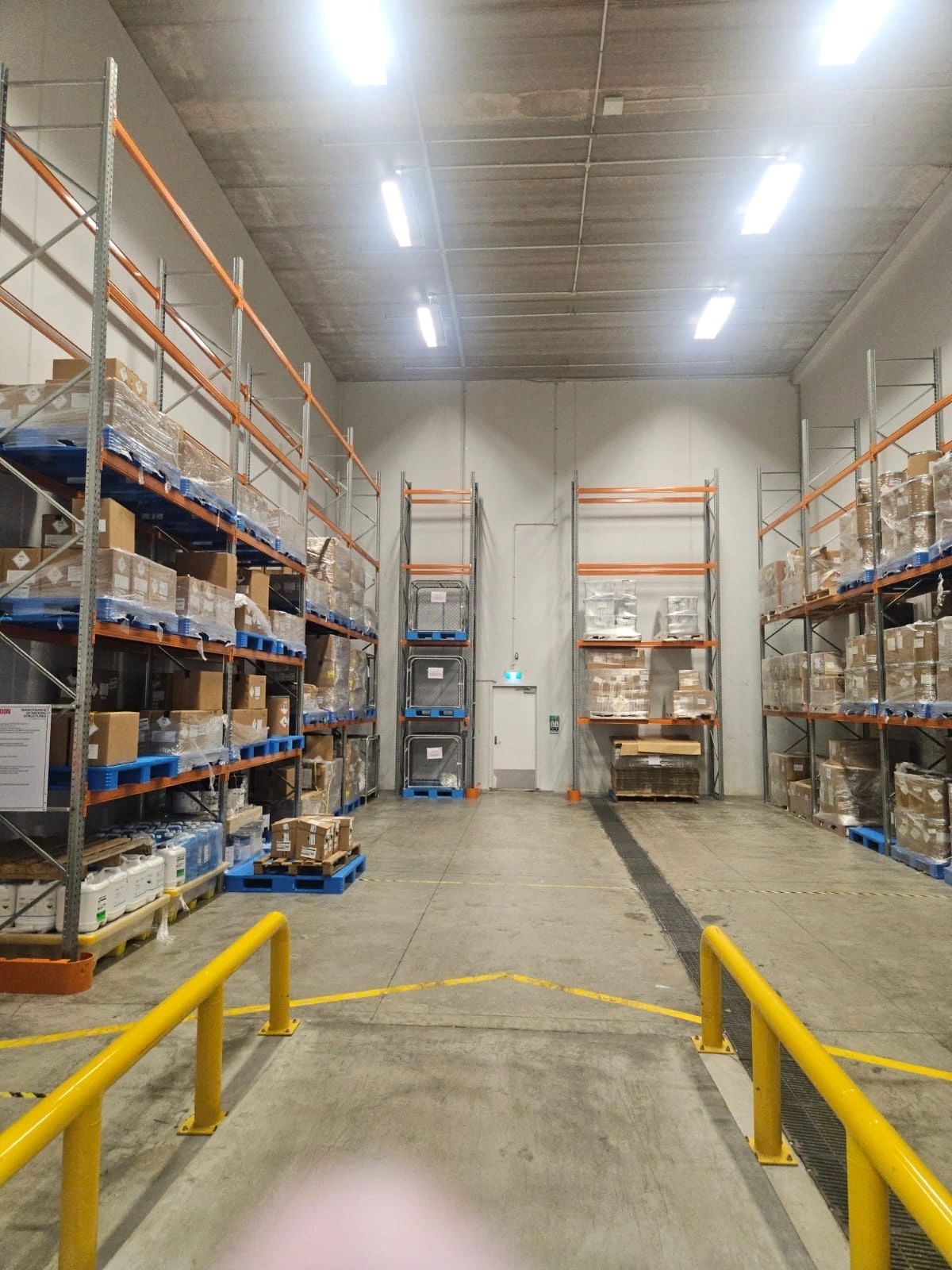 Warehouse interior with safety barriers and industrial racking at a hazardous substances storage facility